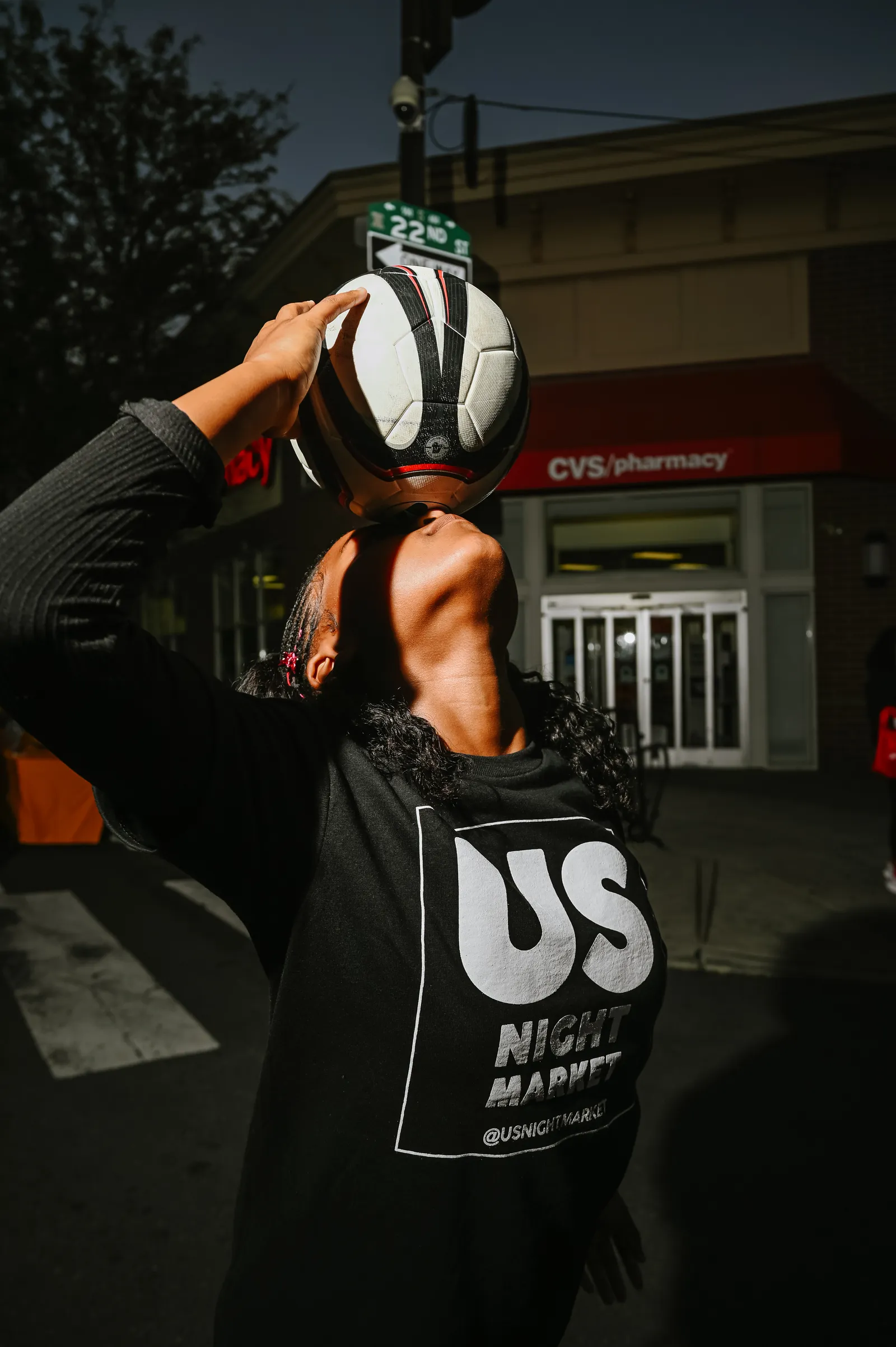 Athlete balancing soccer ball on head under city lights at night
