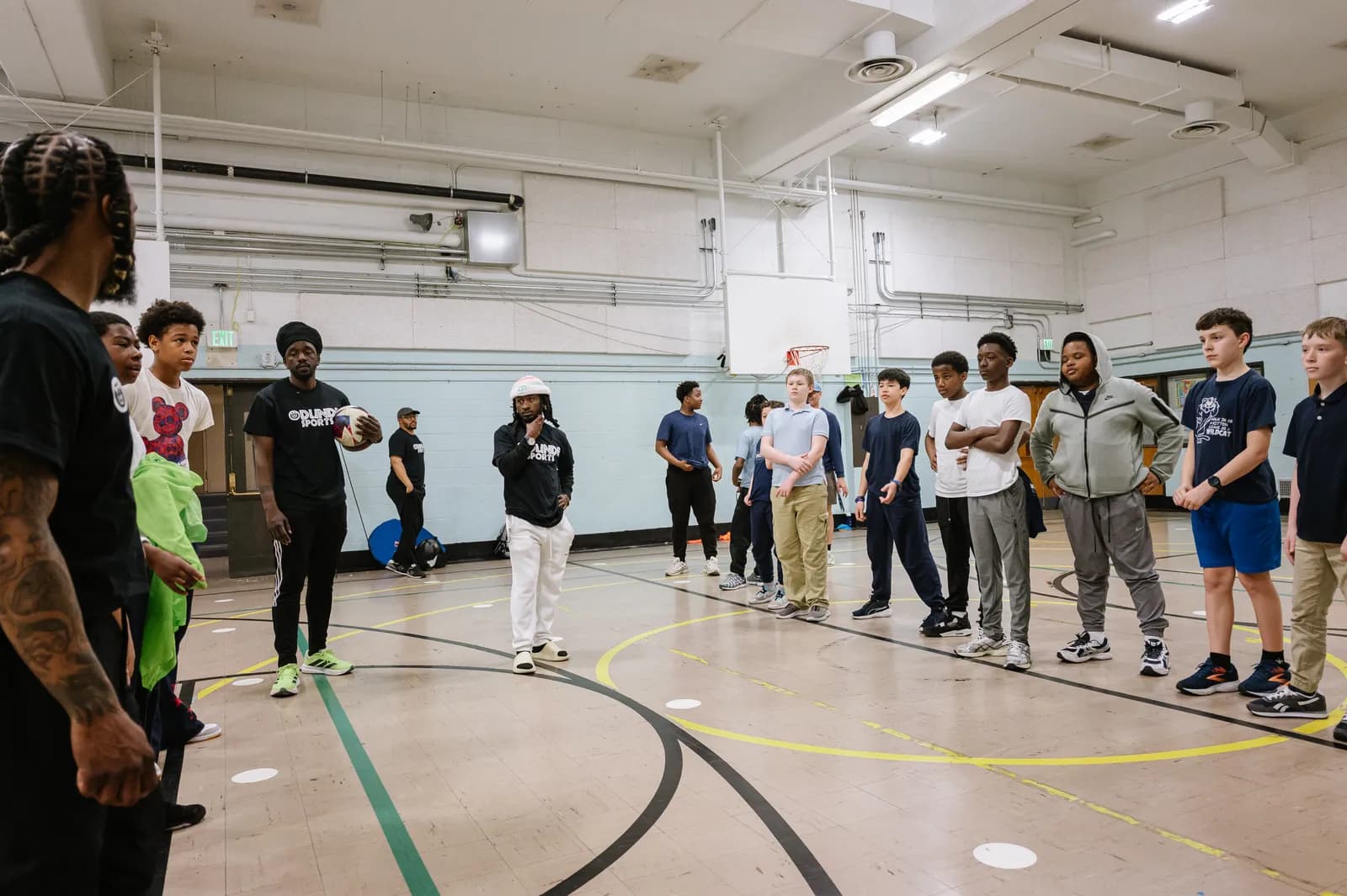 Coach addressing youth athletes gathered in a circle during gym session