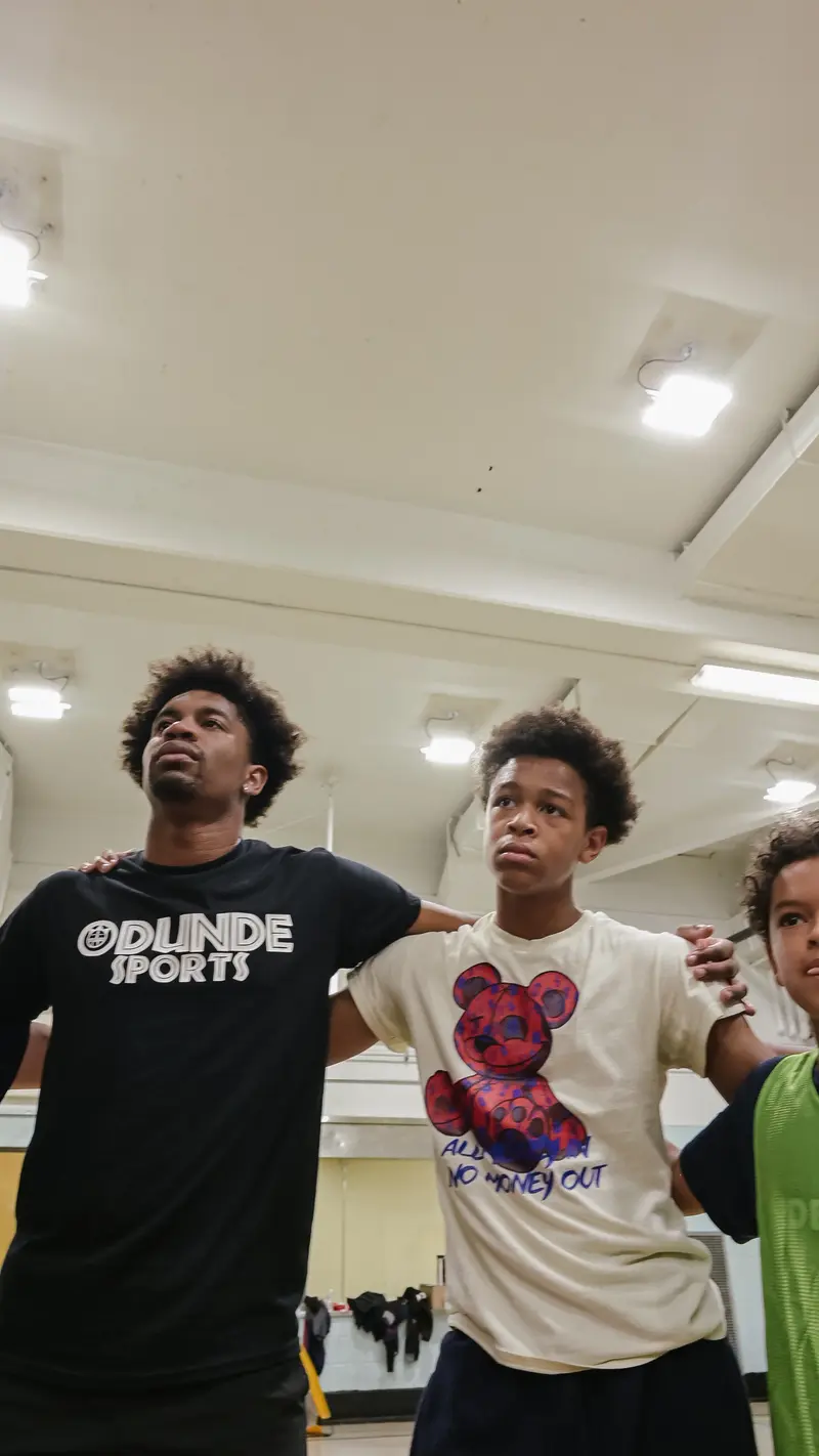 Coach and young athletes with arms linked showing team unity