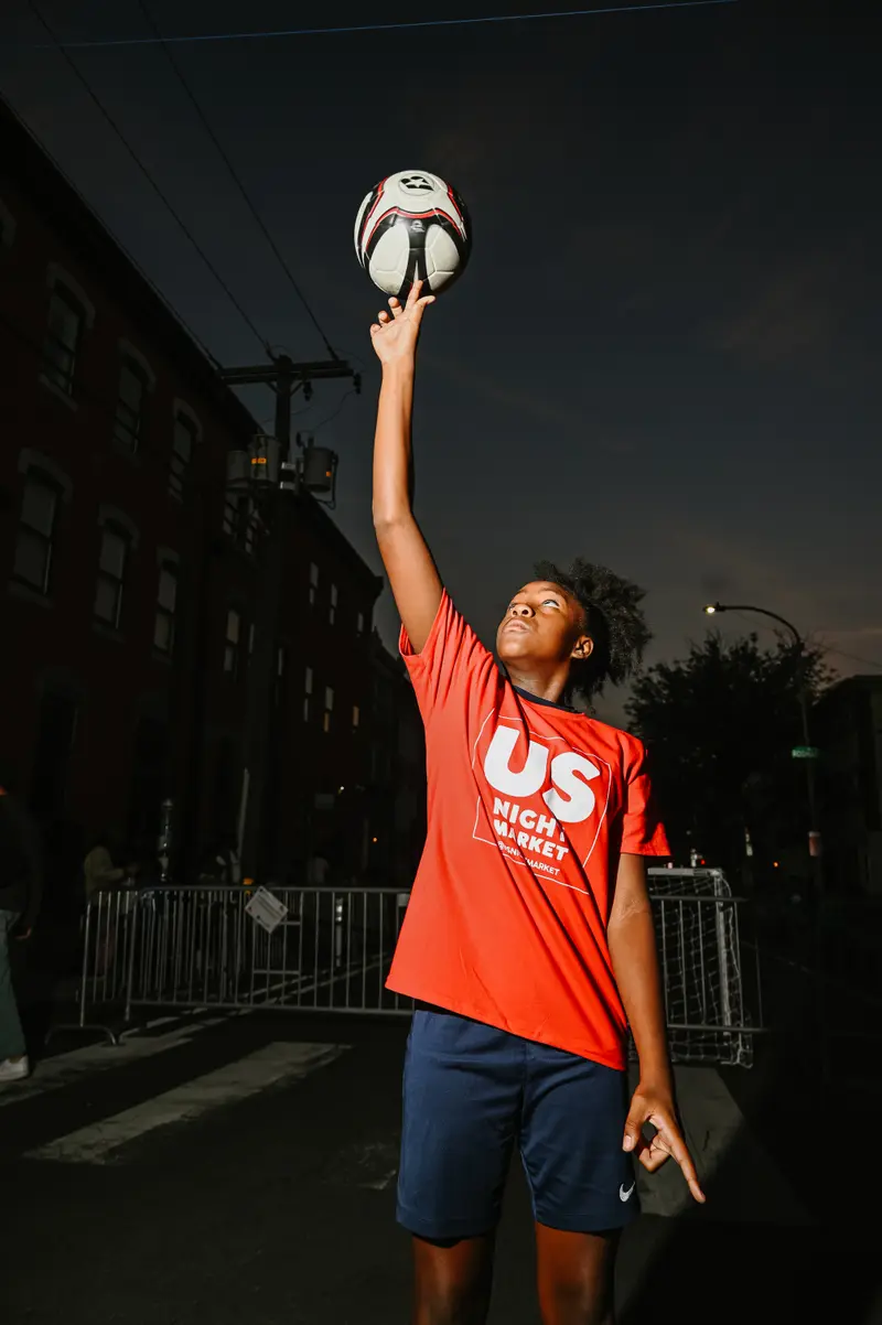 Young athlete reaching for soccer ball against the night sky