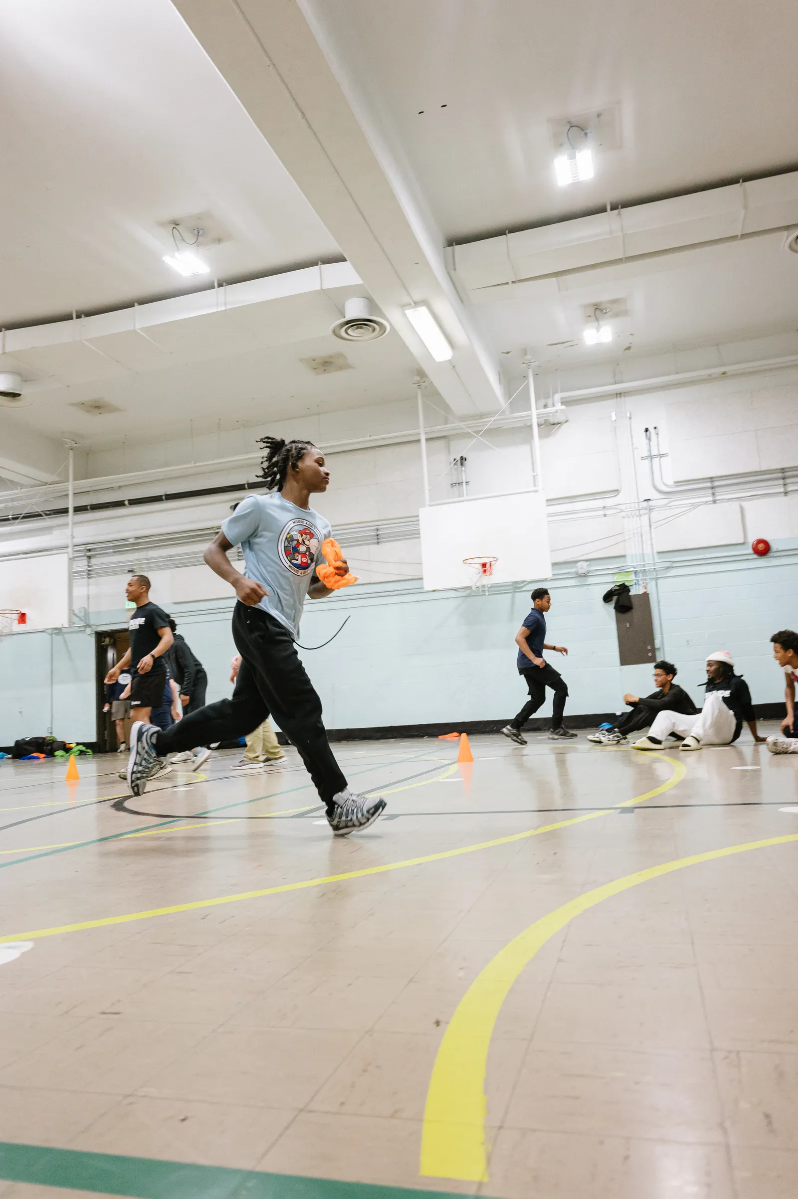 Youth athlete sprinting with orange pinnie during training